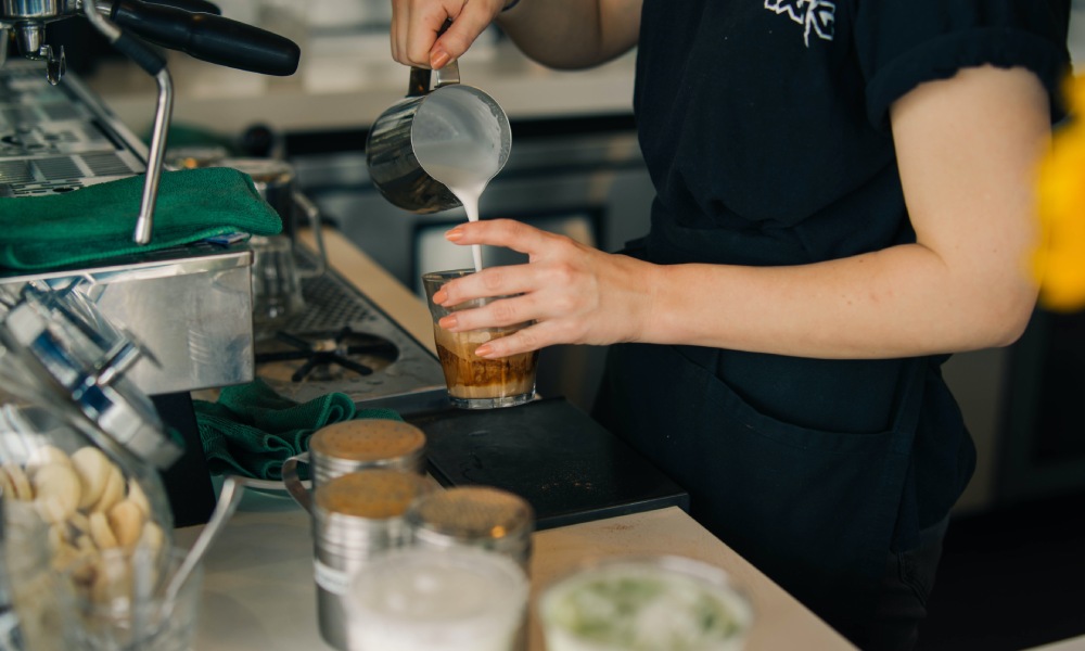 barista pouring milk into a coffee